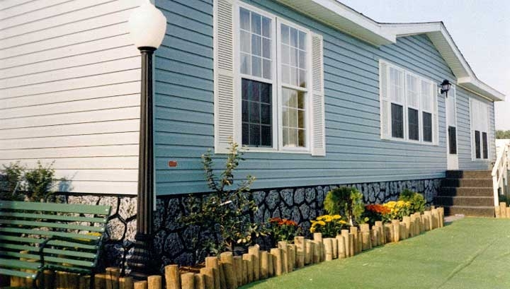 Stone Patterned Skirting with Light Blue Siding and Log Garden Edging
