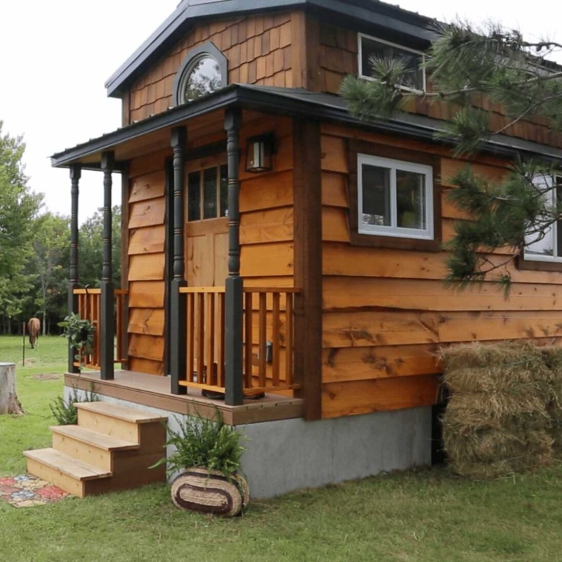 Tiny House Exterior: Gray Concrete-Look Skirting with Rustic Wood Siding
