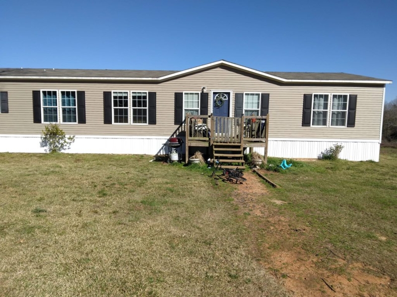 Traditional Beige Mobile Home With Black Shutters And White Skirting