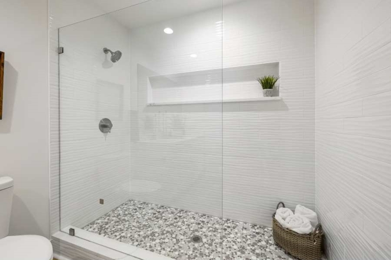 Walk In Shower with Textured Tile and Pebble Mosaic Floor pattern.