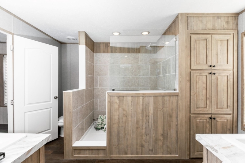 Walk In Shower with Wood Toned Exterior Paneling and Large Tile.