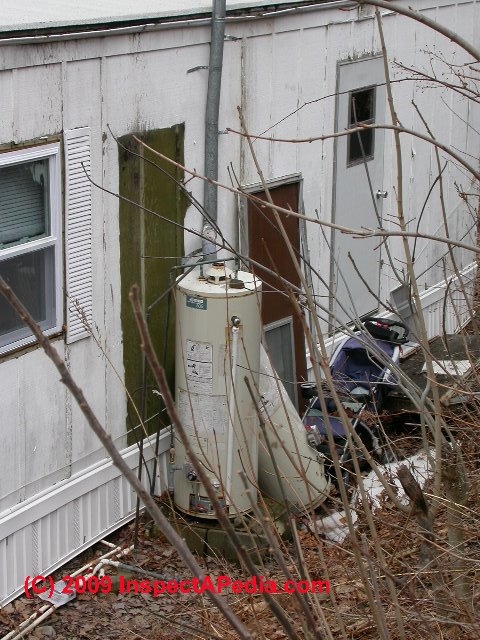 Weathered Exterior Water Heater with Tall Vent Pipe and Exposed Lines