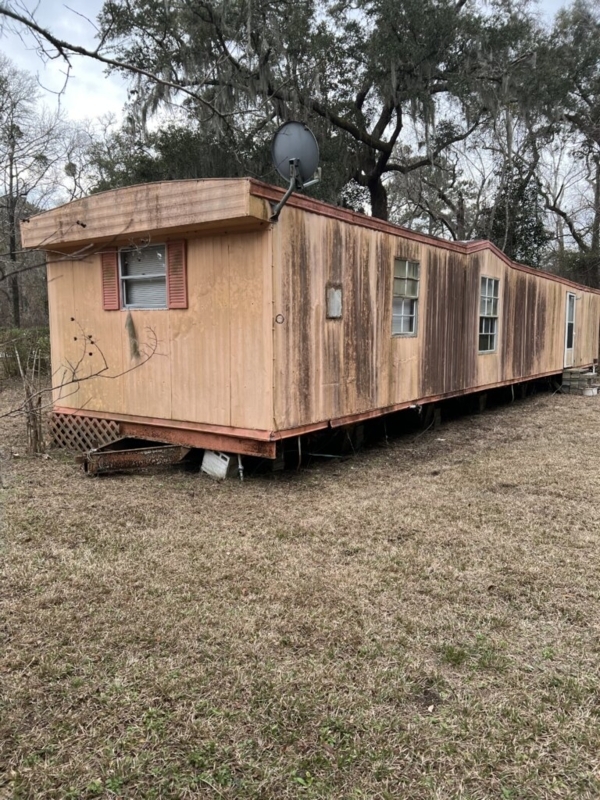 Weathered Single-Wide Mobile Home with Satellite Dish on Wooded Lot