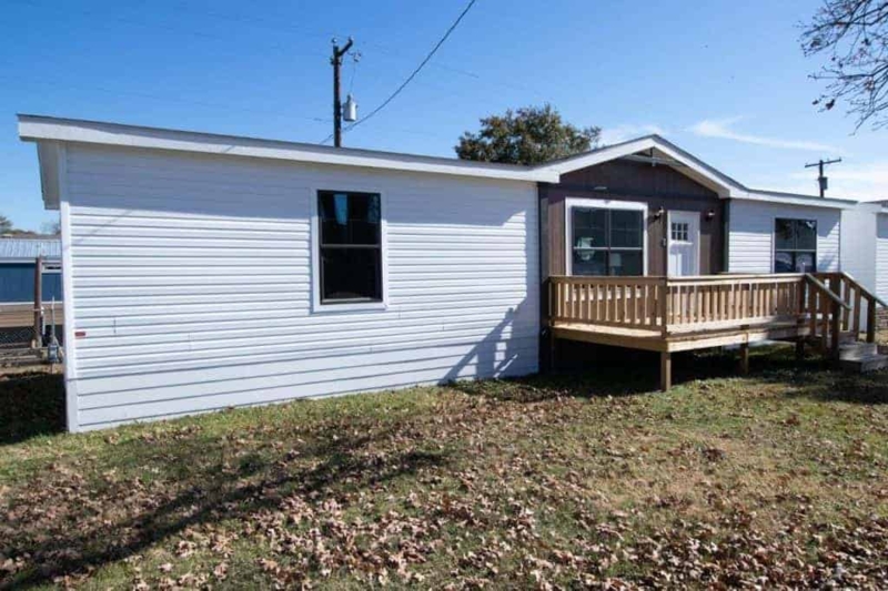 White Double-Wide Mobile Home with a Raised Wooden Entry Deck