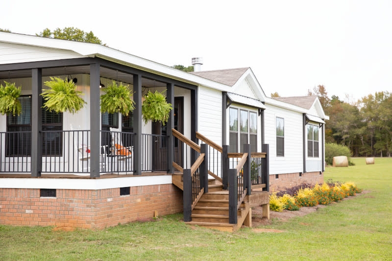 White Manufactured Home with Charcoal Porch Frame and Hanging Ferns