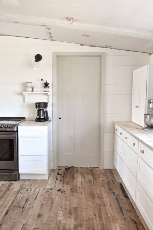 White Shaker Kitchen Cabinets with Shiplap Walls and Distressed Floor