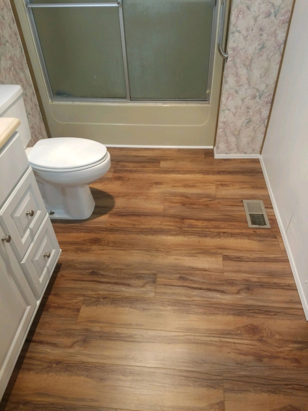 Wood Look Bathroom Flooring in Mobile Home with Floral Wallpaper Accent