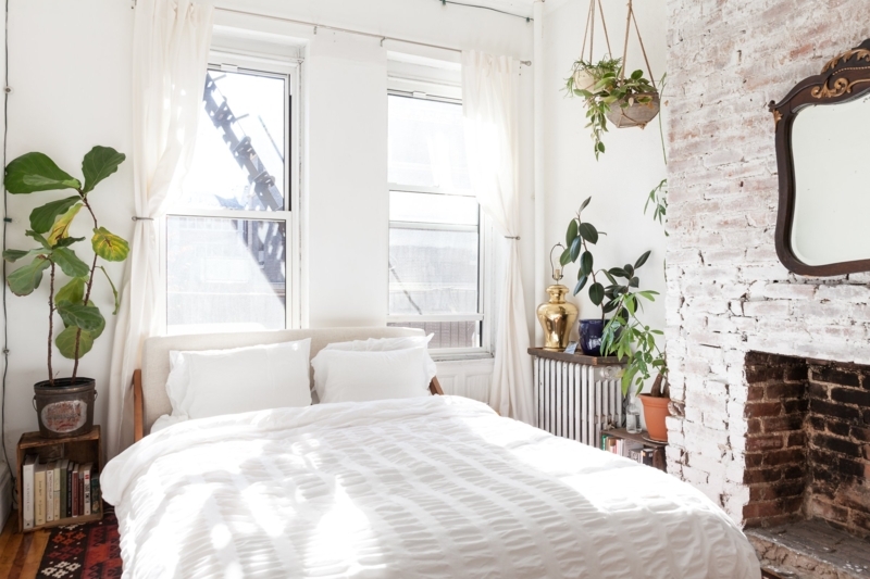 Airy White Bedroom with Exposed Brick Fireplace and Plants