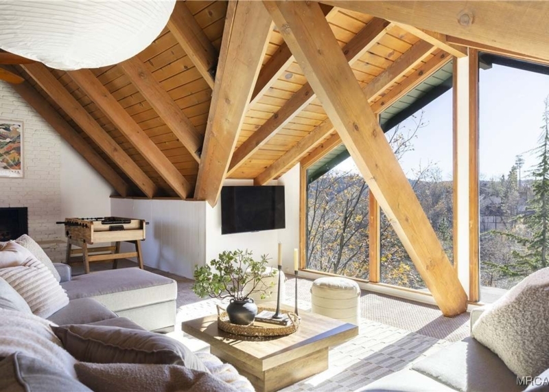 Attic Living Room: Wood-Beamed Ceiling & Angled Windows