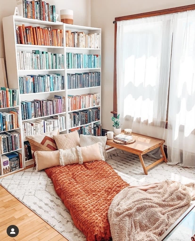 Boho Floor Seating Nook features color-coded bookshelf organization.