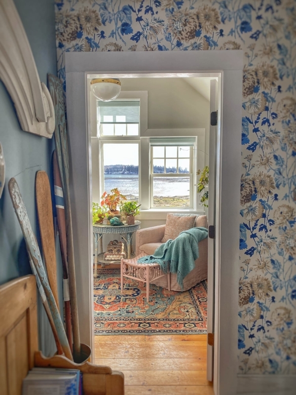 Coastal Armchair Nook: Blush Pink, Teal Throw, Water View.
