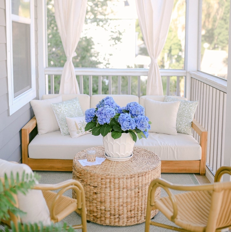 Coastal Porch with Blue Hydrangeas, Woven Drum Table, & Sheer Curtains.