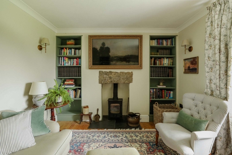 Collected English Living Room with Sage Green Bookshelves & Wood Stove