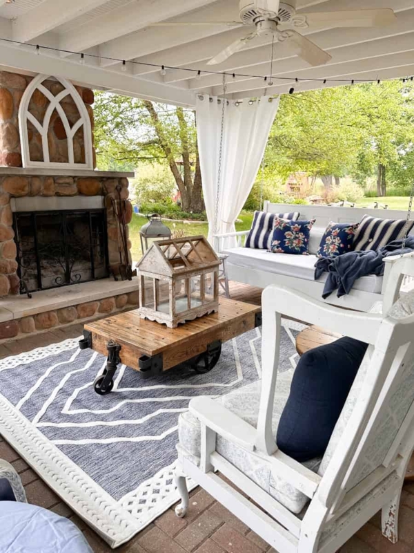 Covered Coastal Porch with Industrial Cart Table and Stone Fireplace