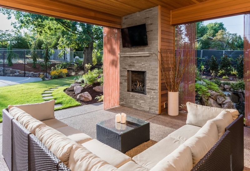 Covered Outdoor Lounge with Wood Paneled Ceiling and Stone Fireplace