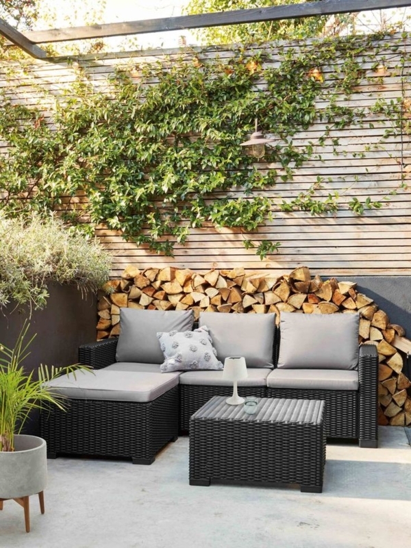 Dark Wicker Outdoor Sectional against Rustic Firewood Wall Backdrop