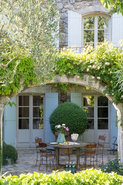 European Courtyard Dining Set framed by Weathered Stone Archway and Vines