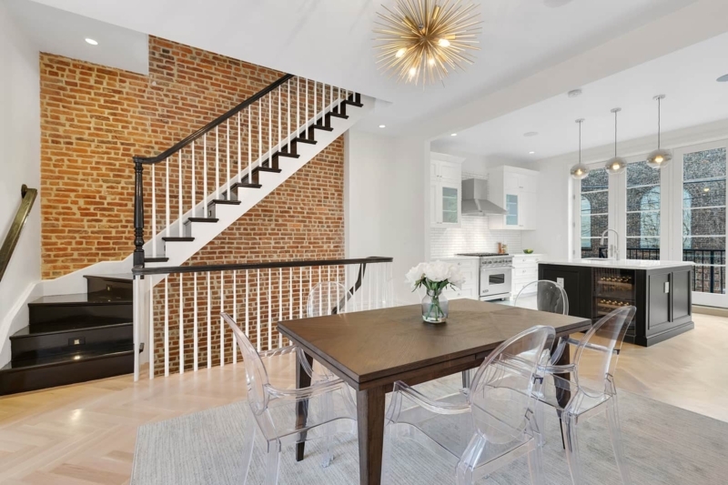 Exposed Brick Dining Room with Clear Acrylic Chairs and Sputnik Chandelier