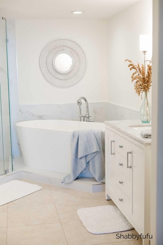 Freestanding Bathtub in All-White Bathroom with Ribbed Sunburst Mirror