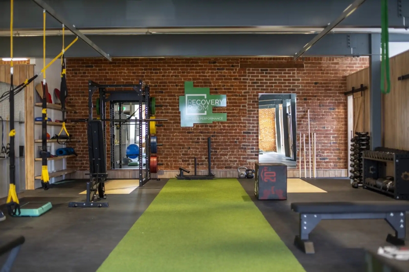 Functional Commercial Gym With Brick Feature Wall And Turf Runway