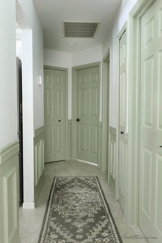 Hallway with Black Door Knobs on Sage Green Paneled Doors