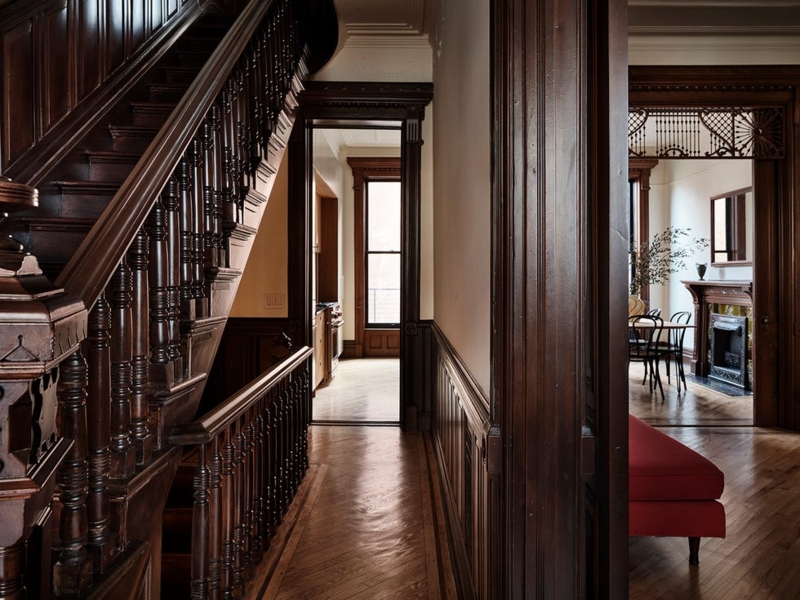 Historic Brownstone Hallway Design With Ornate Dark Wood Staircase