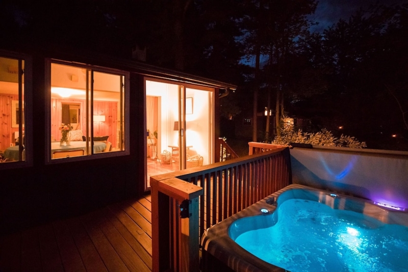Hot Tub on Wood-Toned Deck with Blue Underwater Glow at Night