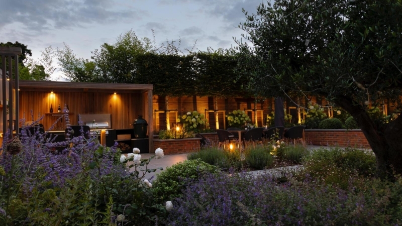 Integrated Outdoor Kitchen: Dramatic Hedge Uplighting & Modern Design