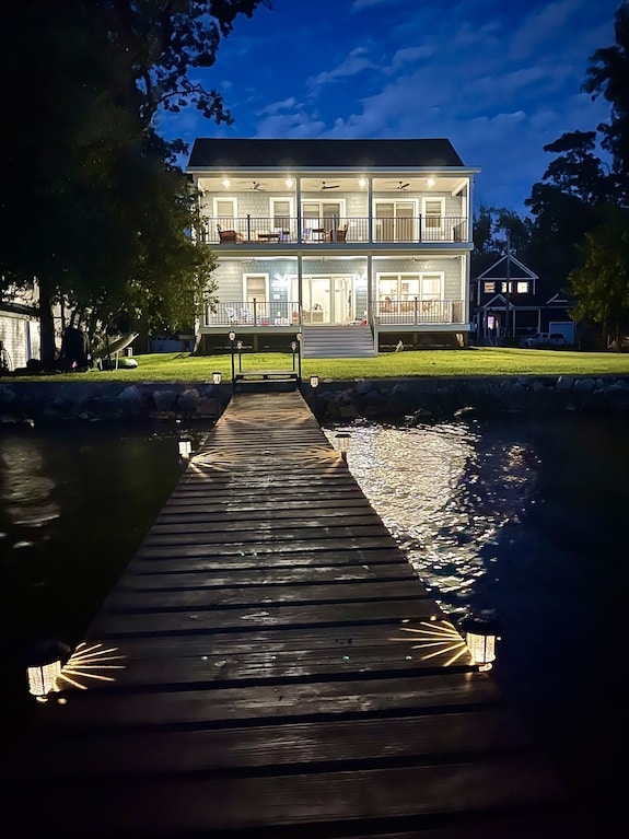 Lakeside Home Evening Exterior with Illuminated Wooden Dock Pathway