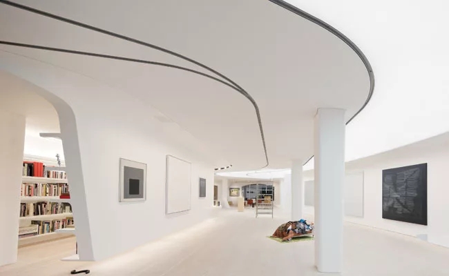 Minimalist Art Gallery Loft: Curved Ceiling Tracks & Built-In Shelves
