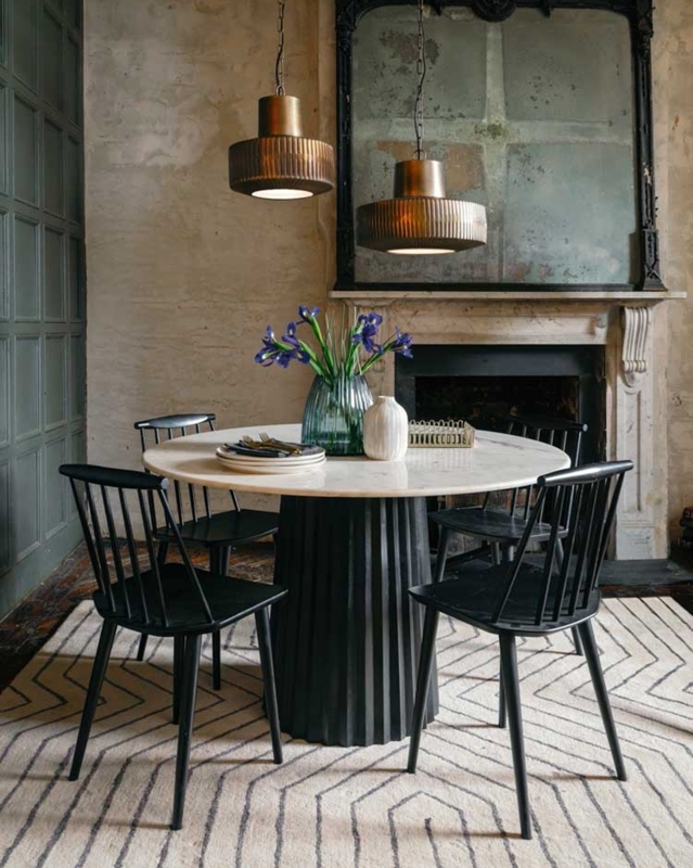 Moody Dining Room with round marble table and chevron pattern rug.