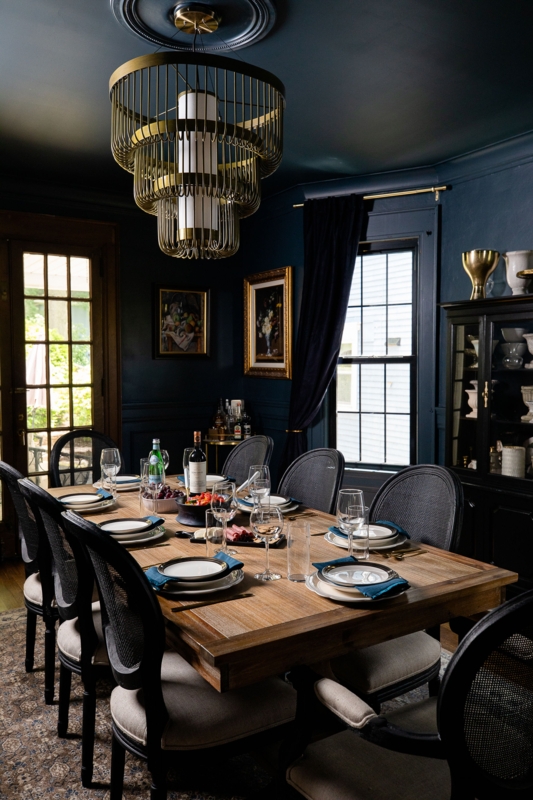 Moody Navy Dining Room featuring a brass tiered chandelier.