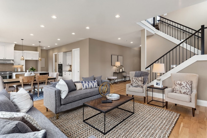 Open Floor Plan Living: Woven Area Rug & Staircase with Black Spindles