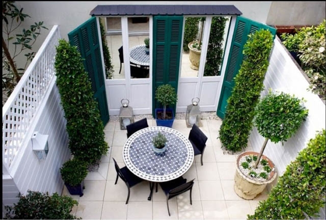Outdoor Dining Set In French Courtyard With Mirrored Shutter Wall