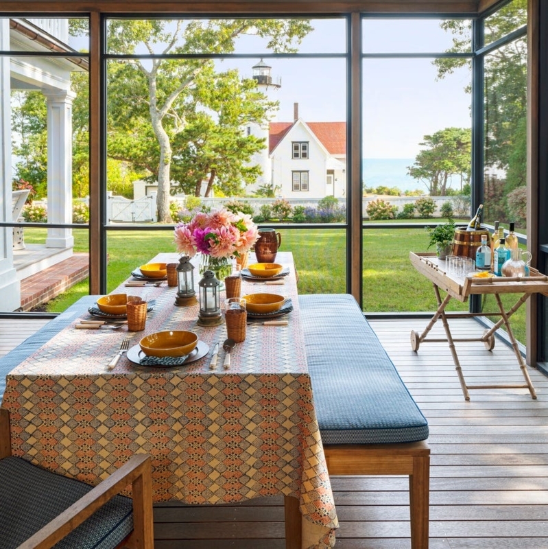 Screened Porch with Lighthouse View, Geometric Tablecloth & Blue Benches.