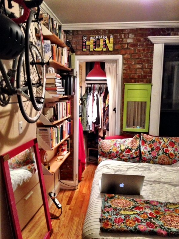 Small Bedroom with Wall Mounted Bicycle and Exposed Brick Wall Storage