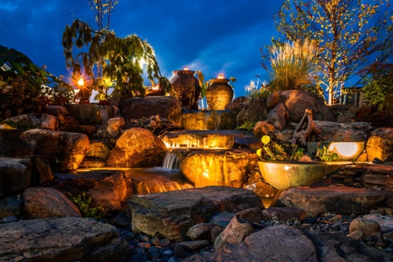 Stone Waterfall with Fire Urns and Dramatic Garden Lighting