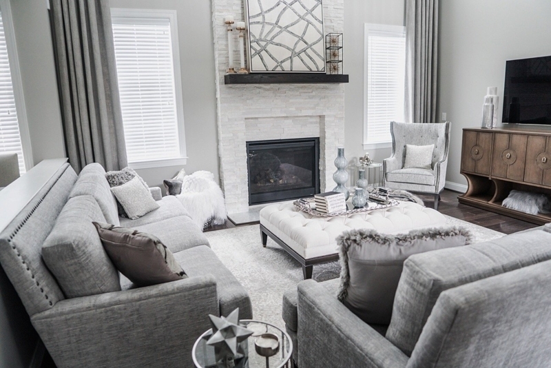 Transitional Grey Living Room with Stacked Stone Fireplace and Tufted Ottoman