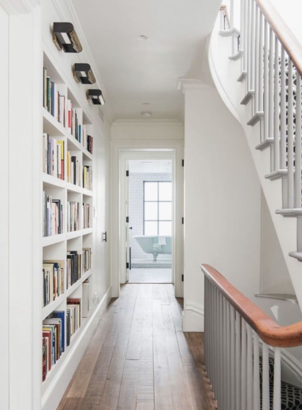 White Hallway Built-In Bookcase with Black Picture Lights & Stairs